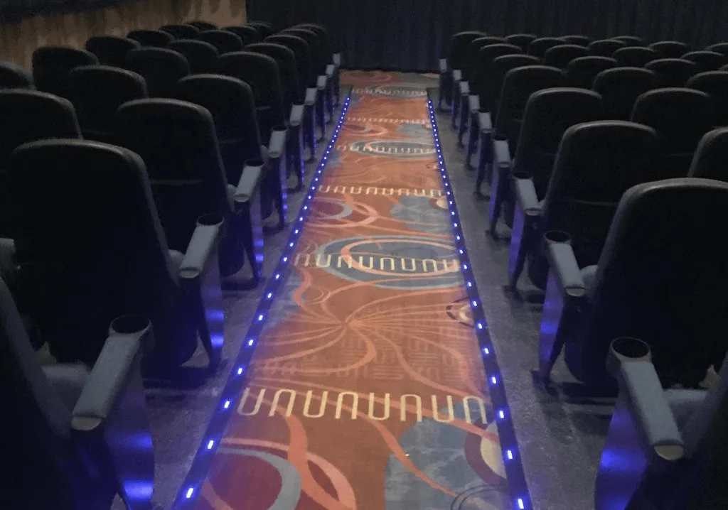Movie theater aisle with patterned commercial carpet and blue LED lighting
