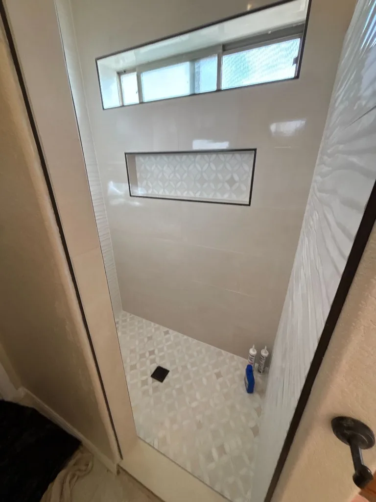 Custom shower with mosaic floor tile, recessed niche, and textured wall tile